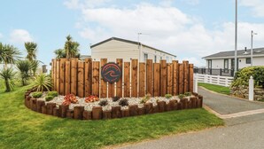 Une maison mobile entourée d’une clôture en bois, avec une pancarte indiquant « Aventura ».