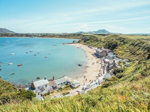 Uma vila costeira com praia, barcos e casas.