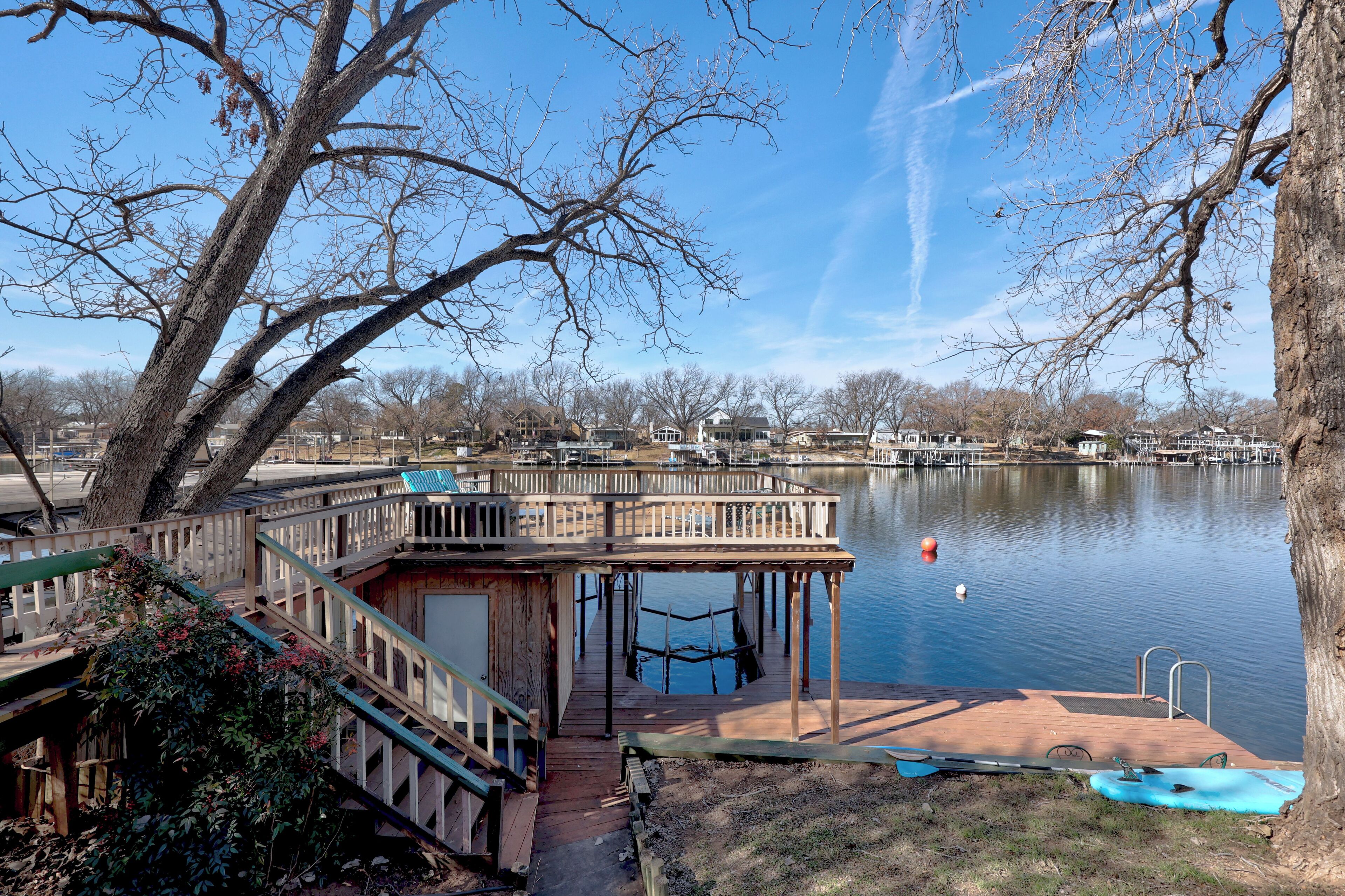 A dock extending into a calm lake with a wooden pier and a small boat docked nearby.