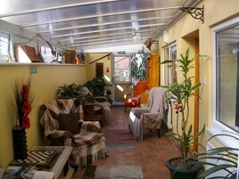 A cozy living room with a fireplace, comfortable seating, and potted plants.