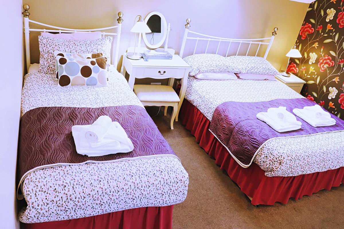 A hotel room with two beds, a vanity with a mirror, and a desk.