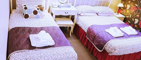 Habitación de hotel con dos camas, un tocador con espejo y un escritorio.