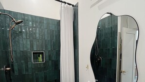 Une salle de bain moderne équipée d’une douche, d’un lavabo et d’un miroir.