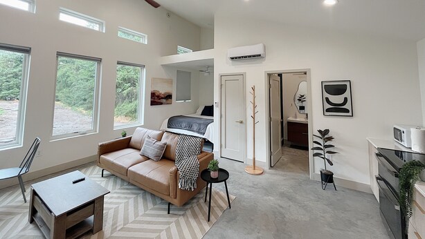 Un salon spacieux avec un plafond haut, un ventilateur de plafond et de grandes fenêtres.