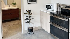 Une cuisine moderne équipée d’un four à micro-ondes, d’un four traditionnel et agrémentée d’une plante en pot.