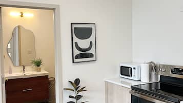 A modern kitchen with a microwave, oven, and a potted plant.