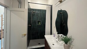 Une salle de bain avec une douche, un lavabo et un miroir.