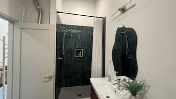 A bathroom with a shower, a sink, and a mirror.