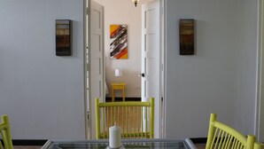 A dining area with a glass table, a candle, and a chair with a yellow backrest.