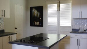 A modern kitchen with a central island, white cabinets, and a black backsplash.