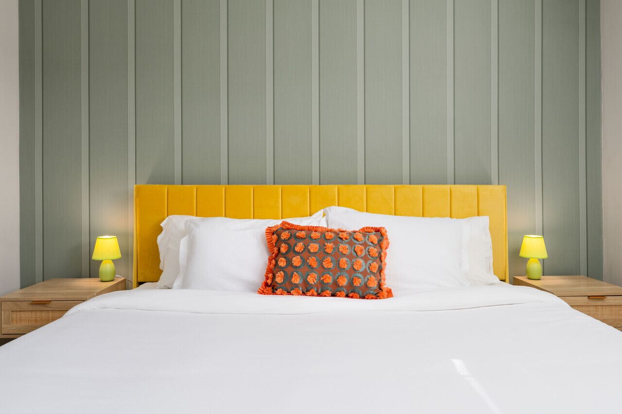 Una camera d'albergo con un letto, due comodini e lampade.