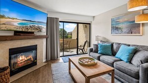 Una sala de estar con chimenea, televisor, sofá y comedor con mesa y sillas.