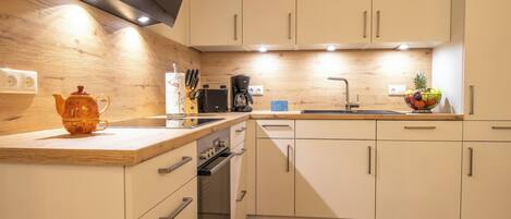 A modern kitchen with wooden cabinets, a coffee maker, and a fruit bowl.