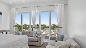 Un dormitorio moderno con una cama grande, dos sofás y un balcón con mobiliario exterior.