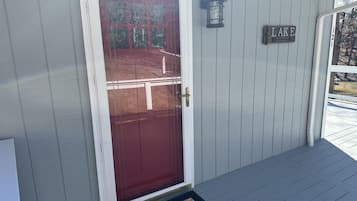 A house with a red door, a sign reading "LAKE", and a small porch area.