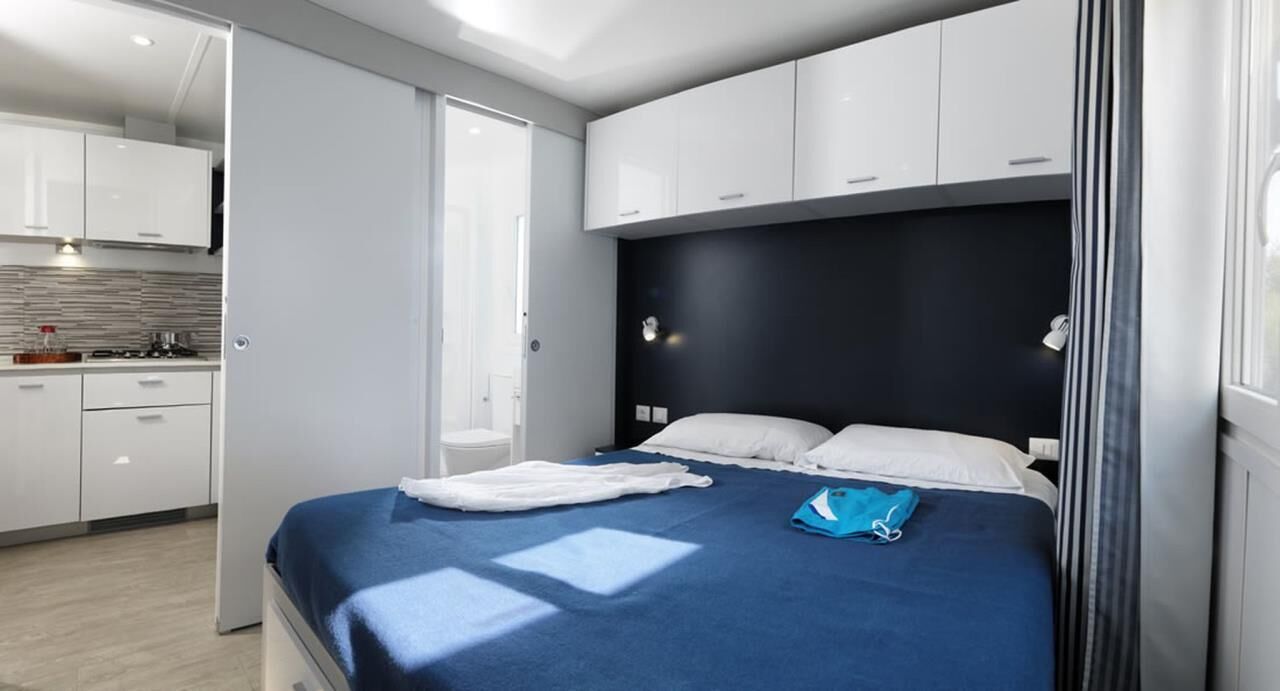 Ein modernes Hotelzimmer mit einem Bett, einer kleinen Küchenzeile und einem Badezimmer.