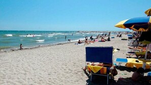 Una playa con gente tomando el sol y nadando.