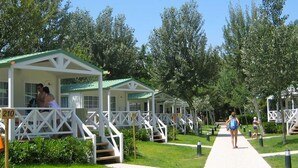 A row of white cabins with green roofs, numbered 210 and 211, connected by a pathway.