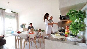 Una cocina moderna con comedor, televisor y planta.