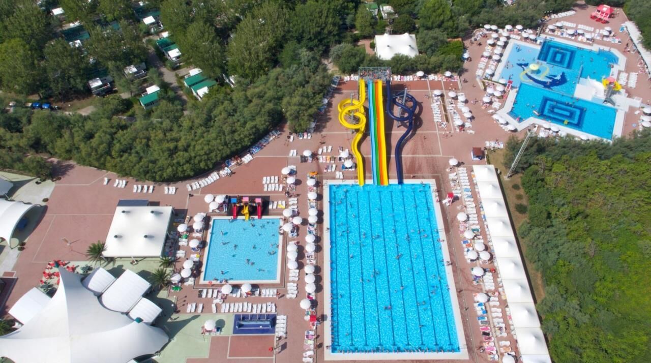 Luchtbeeld van een resort met meerdere zwembaden, een waterpark en een groot centraal zwembad.