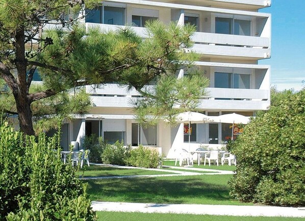 A modern multi-story building with a flat roof, surrounded by well-maintained greenery and outdoor seating. - Isaresidence three-room apartment Family Studio for 6 people (Isolaverde di Chioggia)