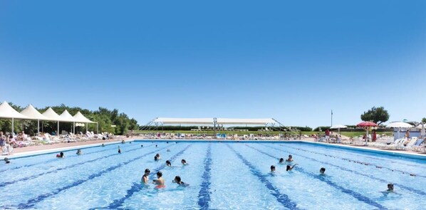 A large outdoor swimming pool with multiple lanes, surrounded by sun loungers and umbrellas. - Isaresidence Studio with pool/sea view for 4 persons (Isolaverde di Chioggia)