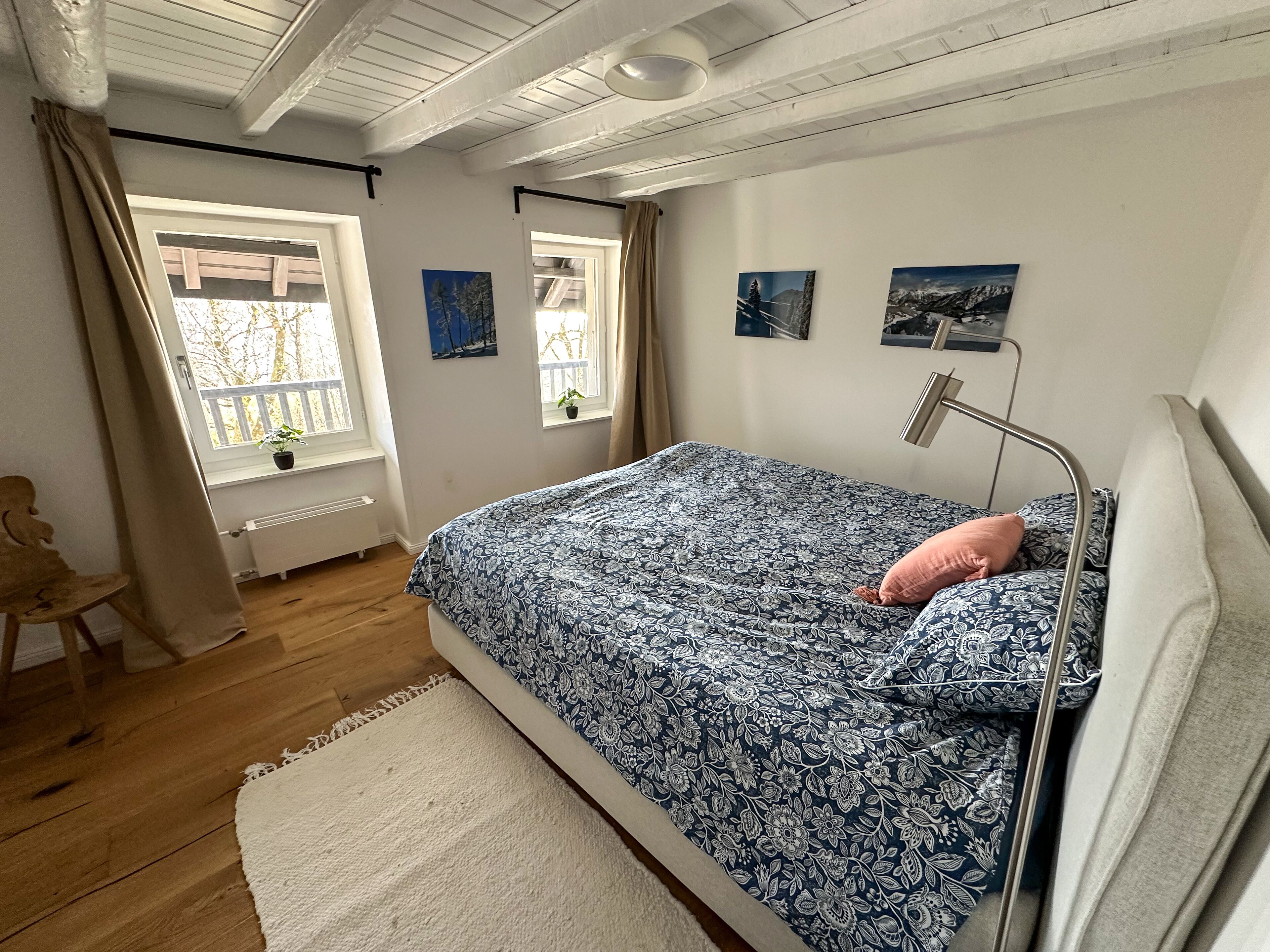 Un dormitorio con cama, mesita de noche, ventana con cortinas y radiador.
