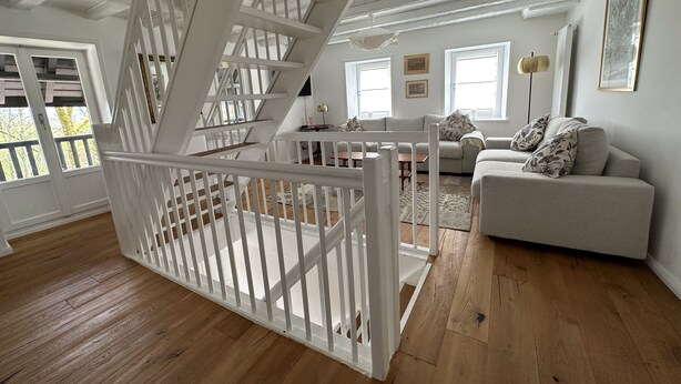 A spacious living room with a white staircase, a sofa set, and a view through large windows. - domaine du deven (Bourg-en-Lavaux)
