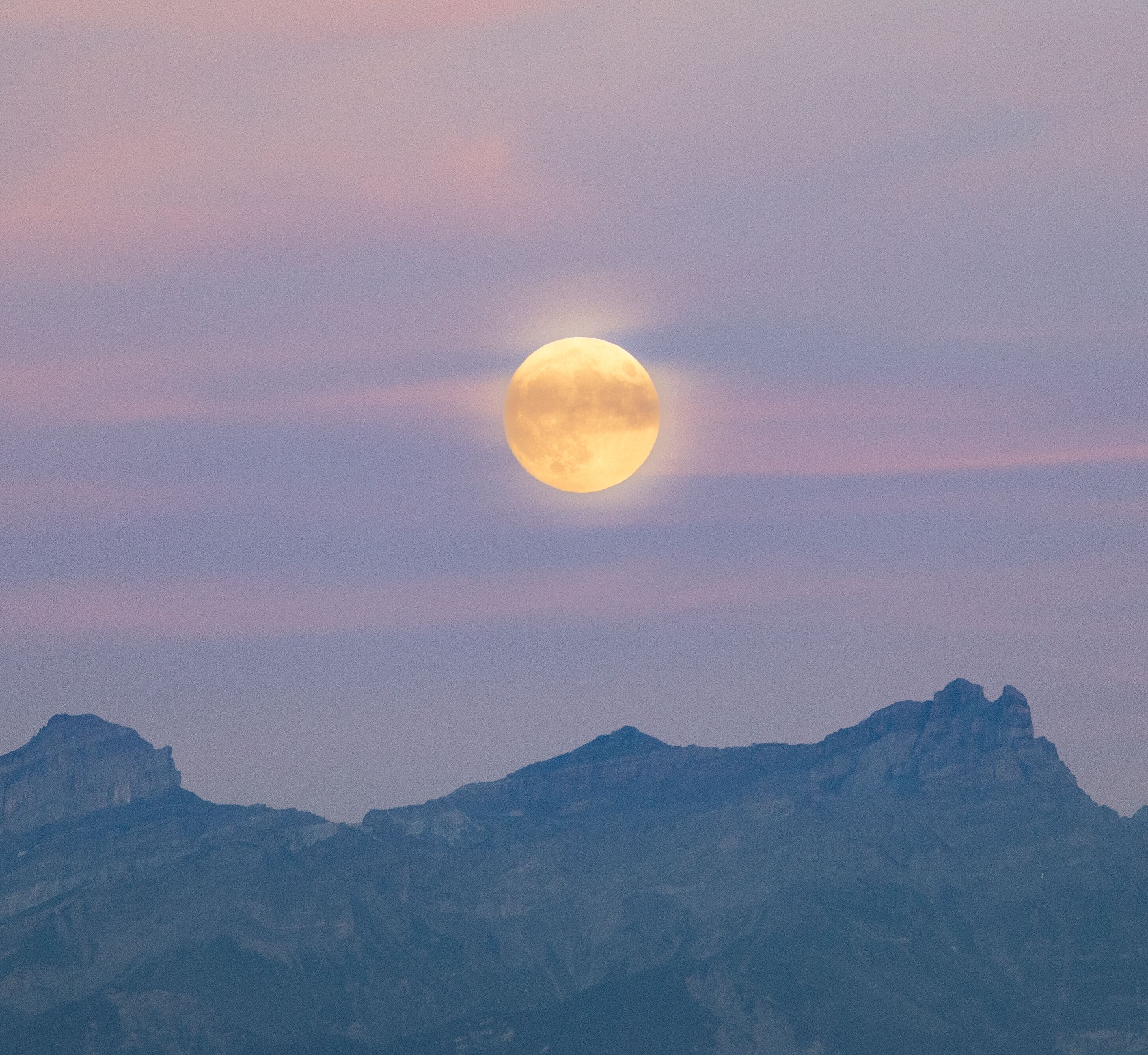 Une pleine lune au-dessus d’une chaîne de montagnes.
