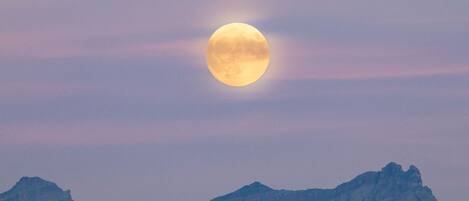 Une pleine lune au-dessus d’une chaîne de montagnes.