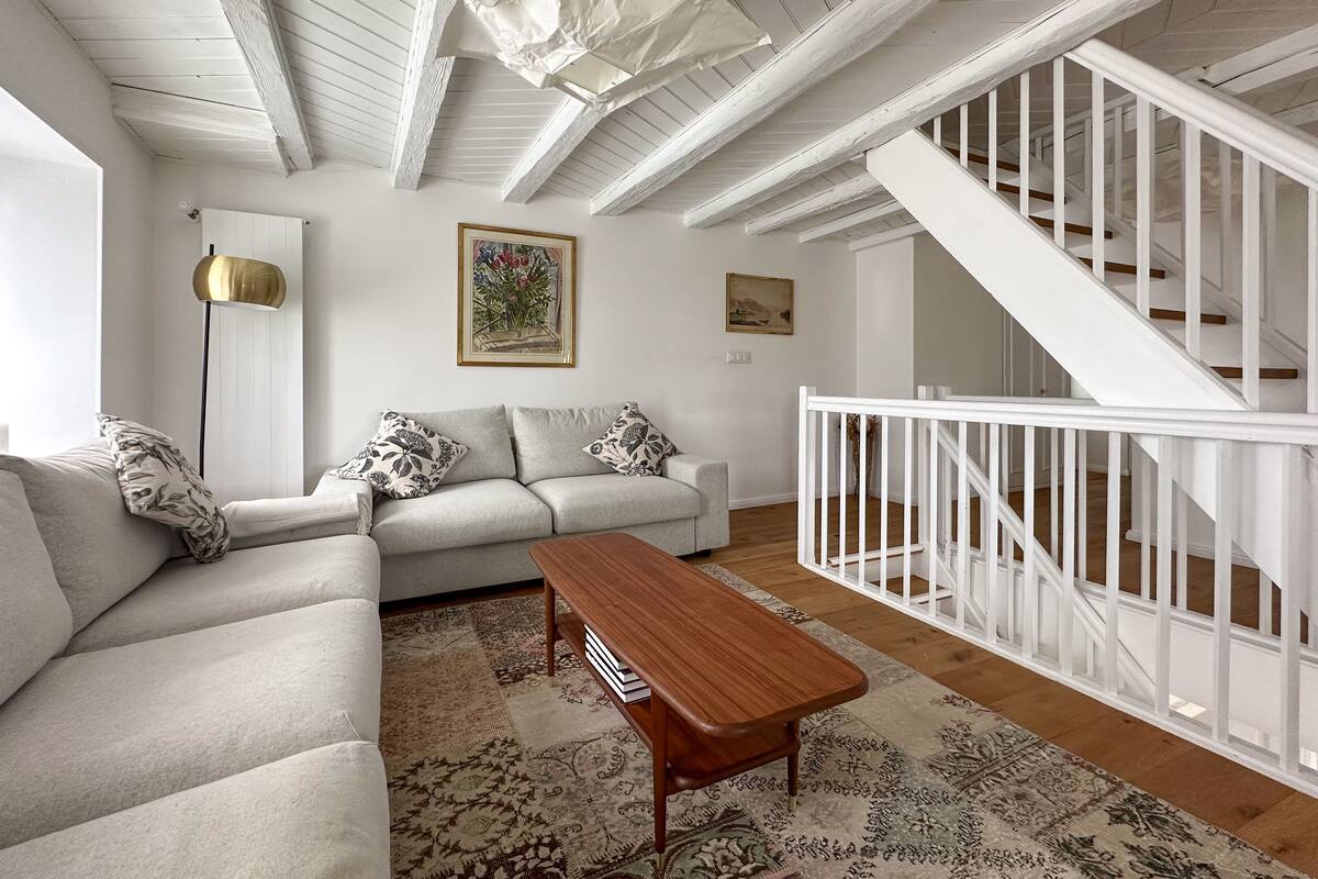 Ein Wohnzimmer mit einer Couch, einem Couchtisch und einer Treppe mit weißen Geländern.