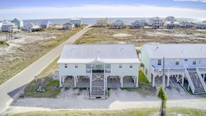 A coastal property with multiple buildings, a paved road, and a beach in the background.