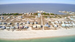 An aerial view of a coastal area with multiple beachfront properties, a clear sky, and a calm sea.