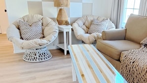 Un salon moderne avec un motif géométrique sur le mur, une table basse à rayures et un canapé beige.