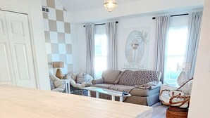 Un vaste espace de vie comprenant une grande table en bois, un canapé et un luminaire suspendu.