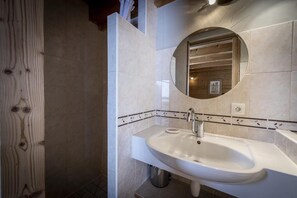 Een badkamer met een wit wastafelmeubel, een spiegel en een betegelde spatwand.