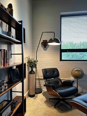 Een moderne kantoorruimte met een lederen stoel, een boekenplank, een hoge vaas en een wereldbol op een standaard.