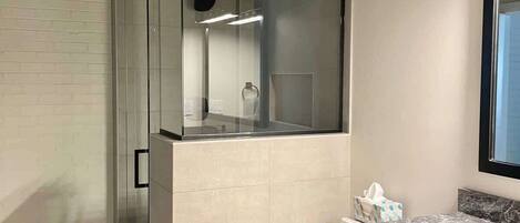 Ein modernes Badezimmer mit einer Duschkabine aus Glas, einer Toilette und einem Waschtisch mit Schubladen.