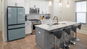 A modern kitchen with white cabinets, stainless steel appliances, a central island with bar stools, and pendant lighting. - R3 at Inlet Beach with Pool access and EV charger (Inlet Beach)