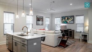 A modern kitchen with a central island, a dining area with a table and chairs, a sofa, and artwork on the walls. - R3 at Inlet Beach with Pool access and EV charger (Inlet Beach)