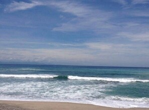 A beach with waves and a clear sky.