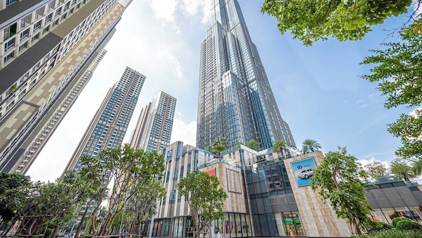 A modern high-rise building with multiple floors, surrounded by trees and other buildings. - Vinhomes Central Park Riverside Elegance (Ho Chi Minh City)