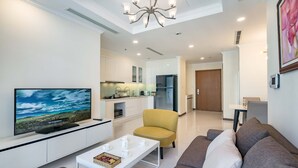 A modern living room with a flat-screen TV, a sofa, a coffee table, and a dining area with a table and chairs. - Vinhomes Central Park Riverside Elegance (Ho Chi Minh City)