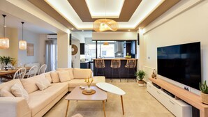 Un salon moderne avec un canapé beige, une table basse et un téléviseur posé sur un meuble en bois.