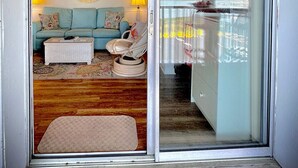 Ein Wohnzimmer mit einem hellblauen Sofa, einem weißen Couchtisch, einem runden Spiegel und zwei Lampen.