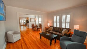 A spacious living room with hardwood flooring, a sofa, a chair, and a coffee table. There is a dining area in the background with a table and chairs. - Toccoa River House- Toccoa River Front-2br/2ba-wifi-walk to town-Free Activities (McCaysville)