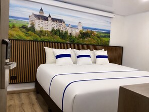 A hotel room with a large bed, wooden headboard, and a mural of a castle on the wall. - Paramount Hotel (Bogotá)