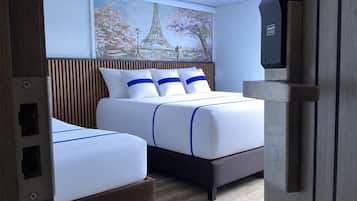 Ein Hotelzimmer mit zwei Betten, einem Gemälde vom Eiffelturm und einer Minibar.