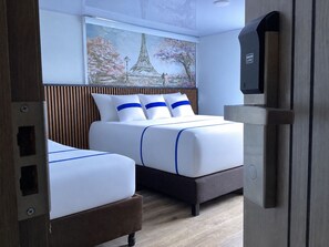 A hotel room with two beds, a painting of the Eiffel Tower, and a minibar. - Paramount Hotel (Bogotá)
