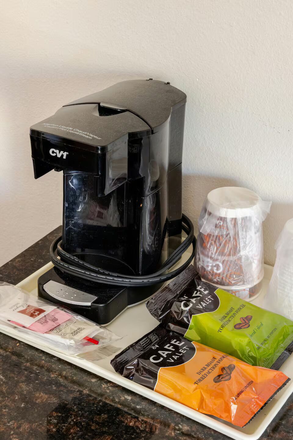 A coffee maker, a coffee pot, and coffee pods on a countertop.